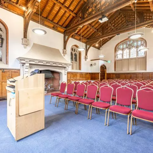 Photo of rows of chairs set out theatre style in a wood panelled room with a high ceiling