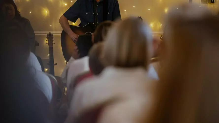 David Clifton playing guitar in front of an audience, fairy lights in the background