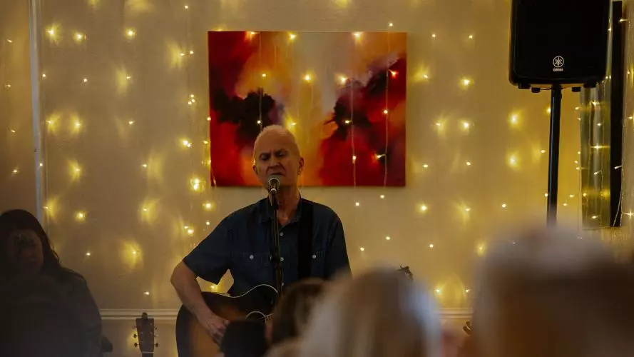 David Clifton playing guitar in front of an audience, fairy lights in the background