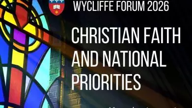 Text Christian Faith and National Priorities on an image of a stained glass window of a cross with light shining through at a podium