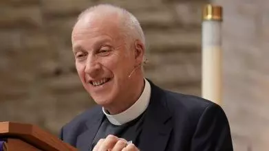 An image of MichaeL Lloyd standing at a lectern preaching