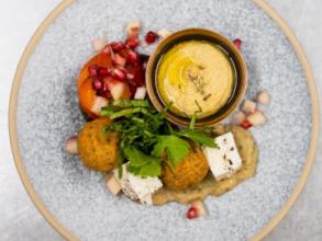 Photo of a Mediterranean themed starter for a formal dinner, with hummus, falafel, feta and pomegranate seeds